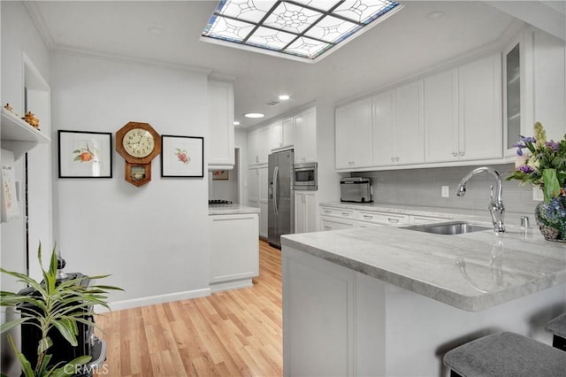 kitchen with kitchen peninsula, appliances with stainless steel finishes, sink, and white cabinetry