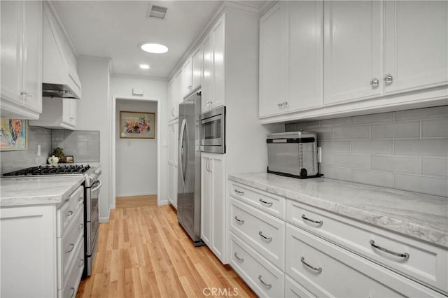 kitchen featuring backsplash, appliances with stainless steel finishes, white cabinetry, and light hardwood / wood-style flooring