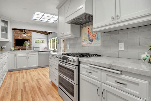 kitchen with white cabinetry, appliances with stainless steel finishes, custom range hood, and lofted ceiling