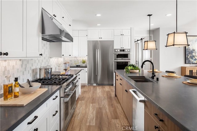 kitchen with light hardwood / wood-style floors, appliances with stainless steel finishes, pendant lighting, white cabinets, and sink