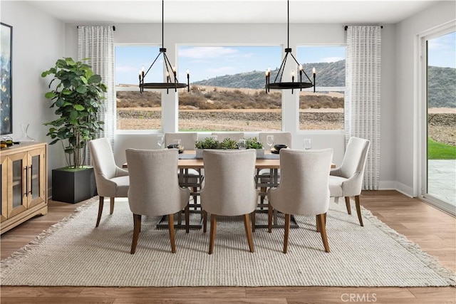 dining area with hardwood / wood-style flooring, a mountain view, and a chandelier