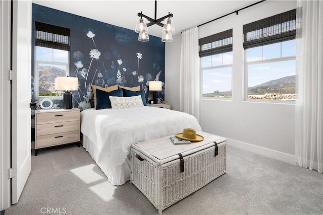 carpeted bedroom featuring an inviting chandelier, a mountain view, and multiple windows