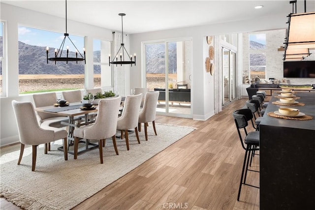 dining room featuring light wood-type flooring, a chandelier, and a mountain view