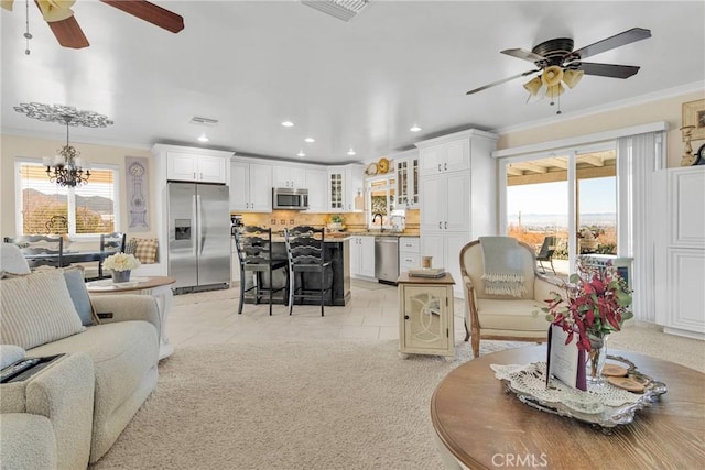 living room with light tile patterned floors, crown molding, ceiling fan with notable chandelier, and sink