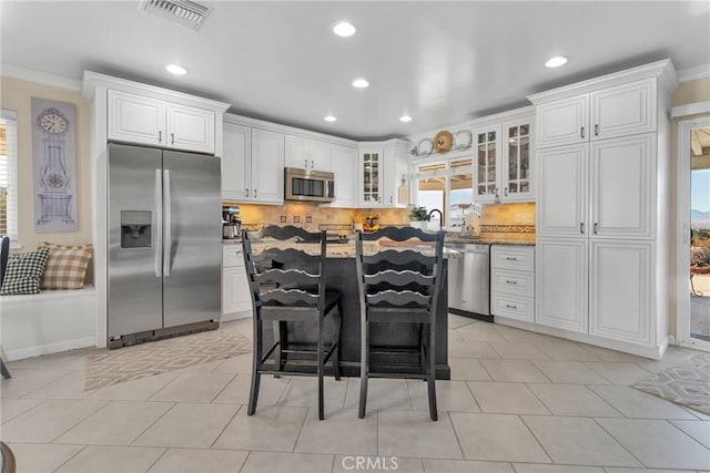 kitchen with appliances with stainless steel finishes, white cabinetry, and a breakfast bar