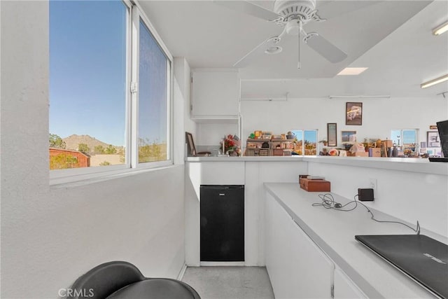 kitchen featuring ceiling fan and white cabinets