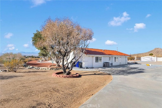 rear view of property featuring central air condition unit, a mountain view, and a patio