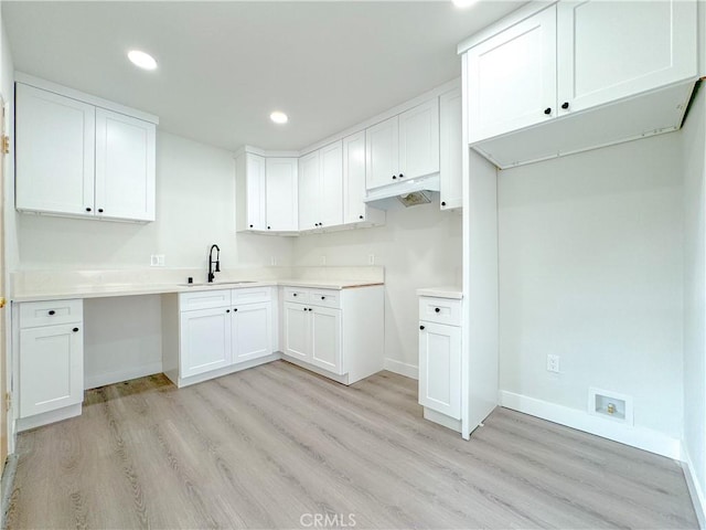 kitchen with light hardwood / wood-style floors, sink, and white cabinets