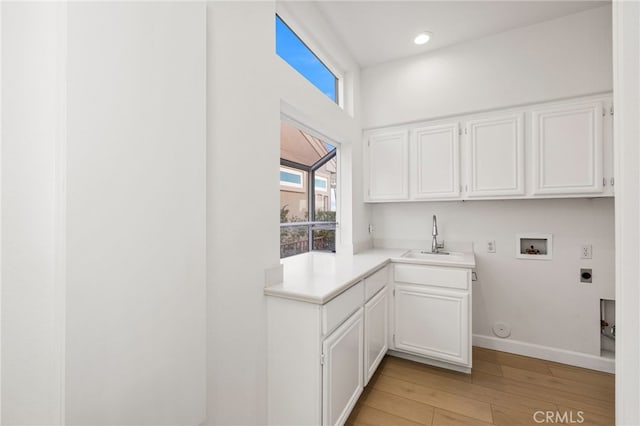 clothes washing area featuring cabinets, sink, hookup for a washing machine, hookup for an electric dryer, and light hardwood / wood-style flooring