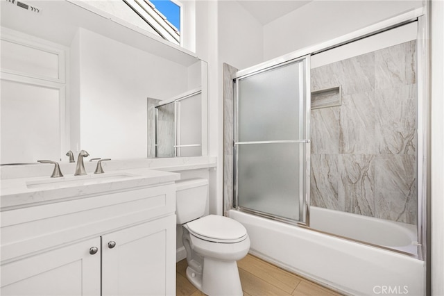 full bathroom featuring toilet, vanity, and shower / bath combination with glass door