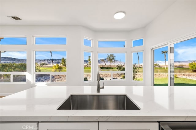 kitchen with light stone countertops, sink, white cabinets, and a mountain view