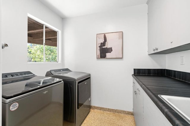 clothes washing area with washer and dryer, cabinets, and sink