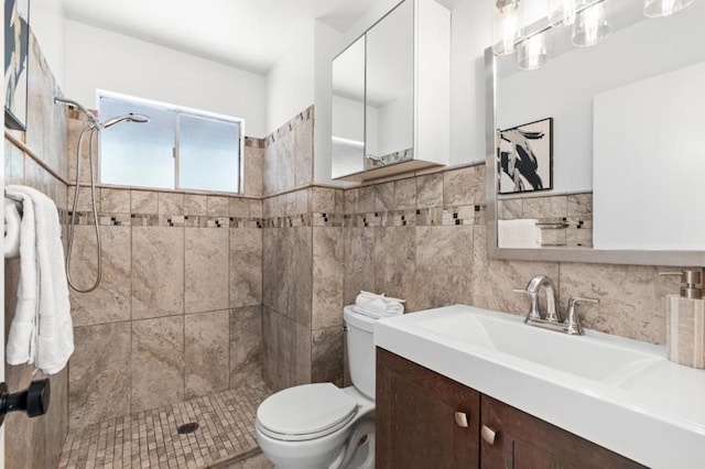 bathroom with toilet, vanity, tile walls, and tiled shower