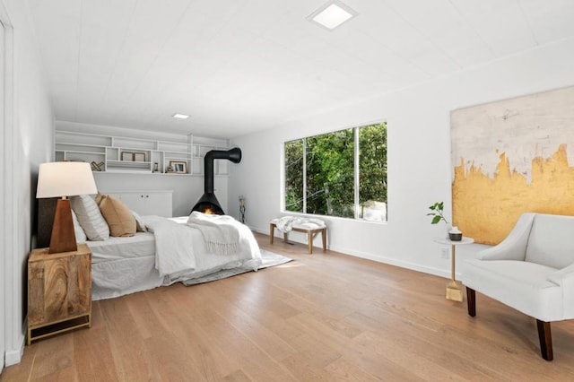 bedroom with a wood stove and light hardwood / wood-style flooring