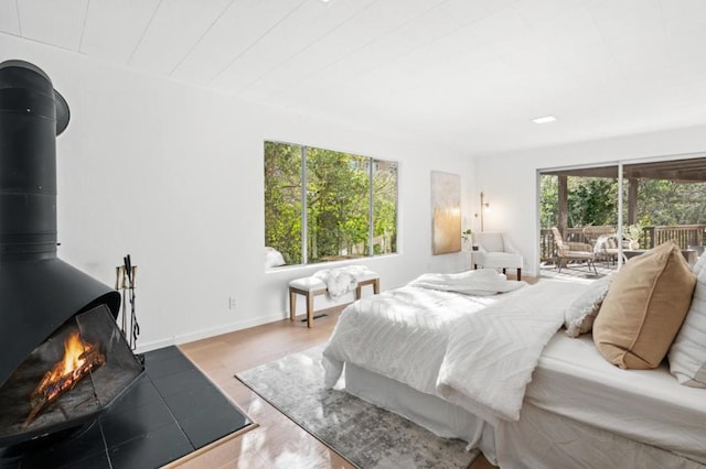 bedroom featuring a wood stove, access to exterior, and light hardwood / wood-style floors