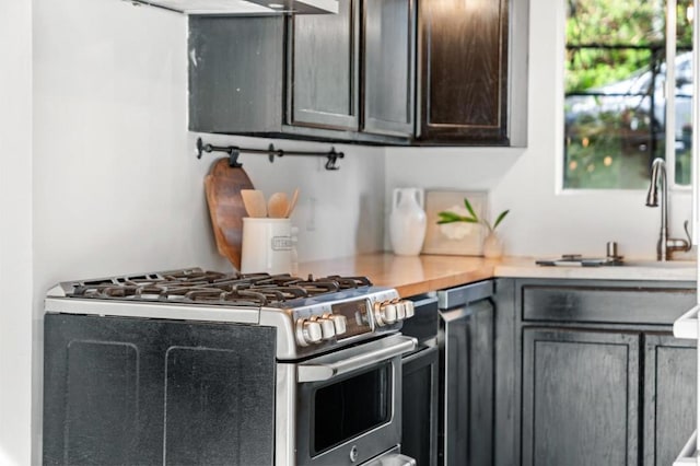 kitchen with gas stove, dark brown cabinetry, and sink