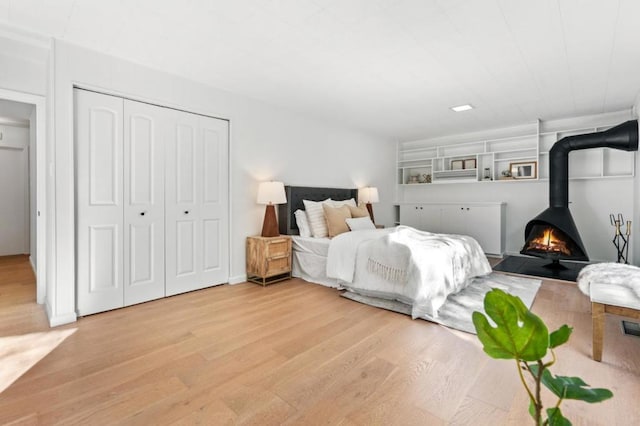 bedroom with a closet, a wood stove, and wood-type flooring