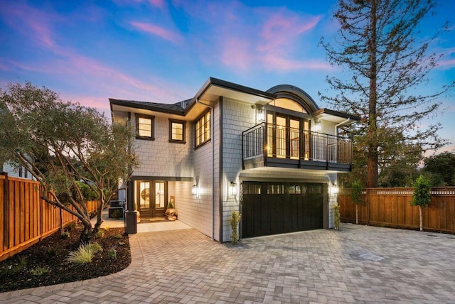 view of front of property featuring french doors, a balcony, and a garage