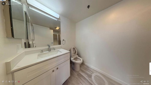 bathroom featuring toilet, wood-type flooring, and vanity