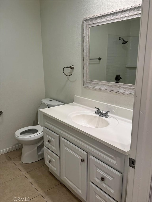 bathroom with toilet, tile patterned flooring, a tile shower, and vanity