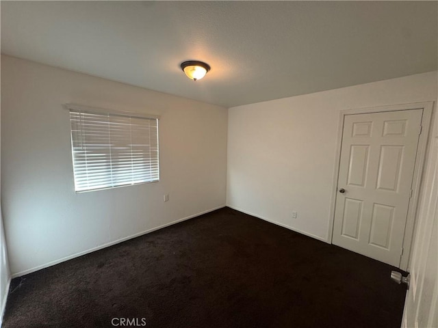 unfurnished room with dark colored carpet