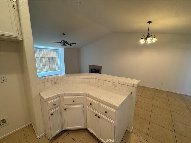 kitchen with vaulted ceiling, pendant lighting, kitchen peninsula, light tile patterned flooring, and white cabinets