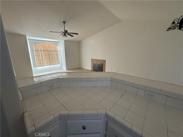 unfurnished living room featuring ceiling fan and a tiled fireplace