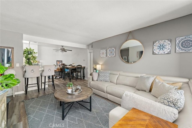 living room featuring ceiling fan and dark wood-type flooring