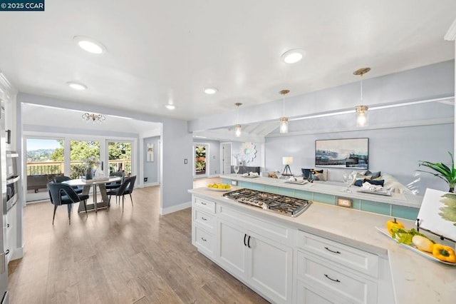 kitchen featuring stainless steel gas stovetop, light hardwood / wood-style floors, white cabinets, and hanging light fixtures