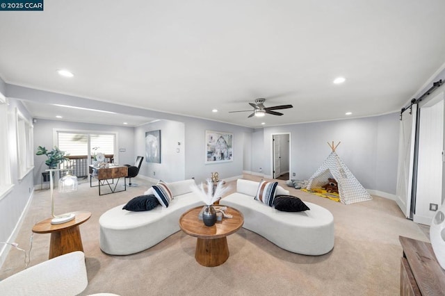 living room with ceiling fan, light colored carpet, ornamental molding, and a barn door