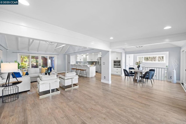 living room with light hardwood / wood-style flooring and vaulted ceiling with beams