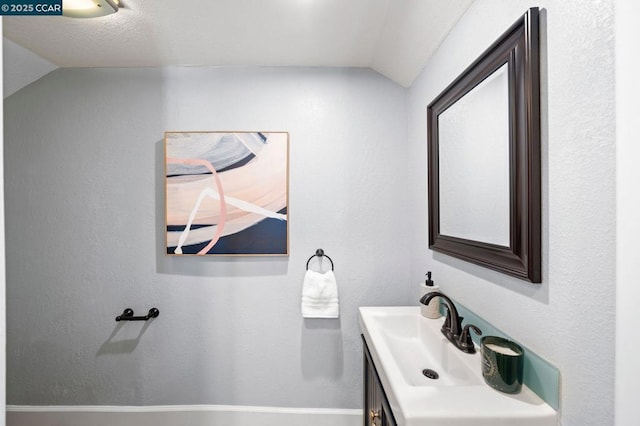 bathroom featuring a textured ceiling, vanity, and vaulted ceiling