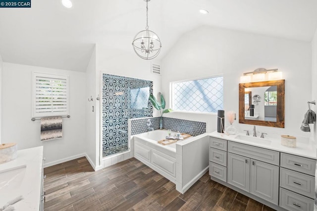 bathroom featuring breakfast area, a notable chandelier, vaulted ceiling, a washtub, and vanity