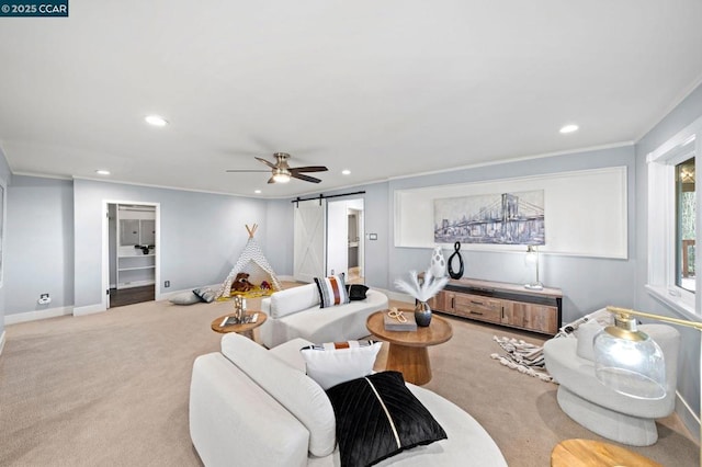 carpeted living room with ceiling fan, ornamental molding, and a barn door