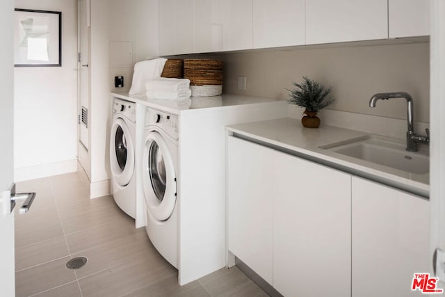 laundry area featuring light tile patterned floors, sink, washing machine and clothes dryer, and cabinets