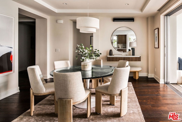 dining area featuring dark hardwood / wood-style flooring and a tray ceiling