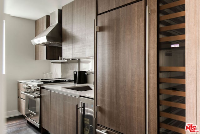 kitchen featuring dark hardwood / wood-style floors, high end range, sink, wall chimney exhaust hood, and beverage cooler