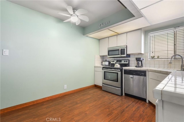 kitchen featuring backsplash, tile countertops, sink, appliances with stainless steel finishes, and white cabinets