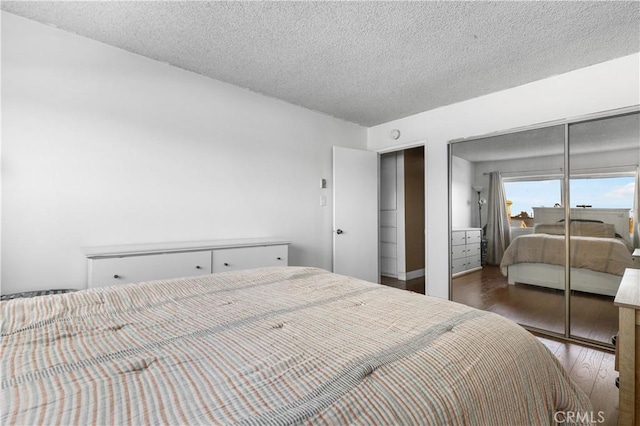 bedroom with a textured ceiling, dark hardwood / wood-style floors, and a closet