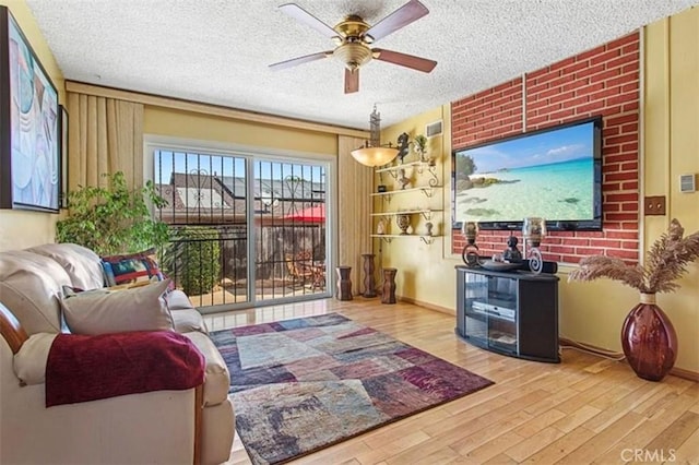 living room with ceiling fan, brick wall, a textured ceiling, and hardwood / wood-style flooring