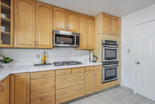 kitchen featuring light tile patterned floors, stainless steel appliances, and decorative backsplash