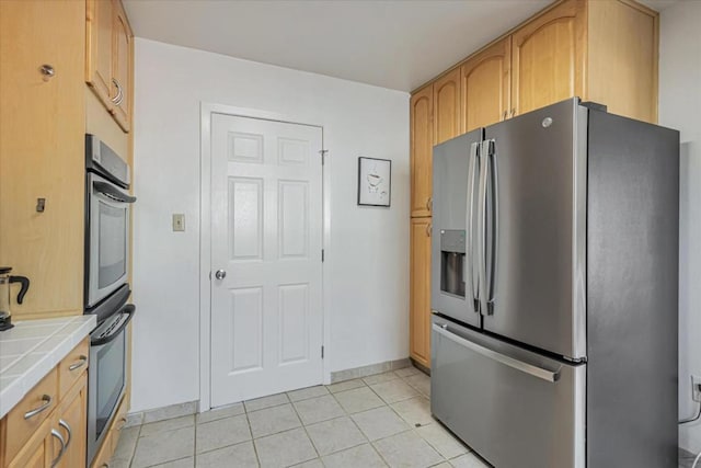 kitchen featuring light tile patterned flooring, stainless steel appliances, and tile countertops