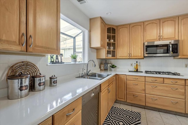 kitchen featuring dishwasher, tasteful backsplash, sink, gas stovetop, and light tile patterned floors