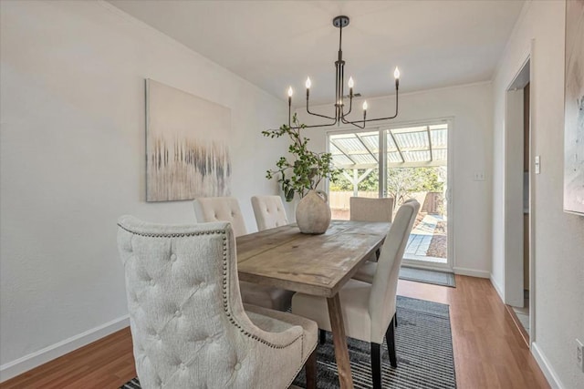 dining space featuring wood-type flooring and an inviting chandelier