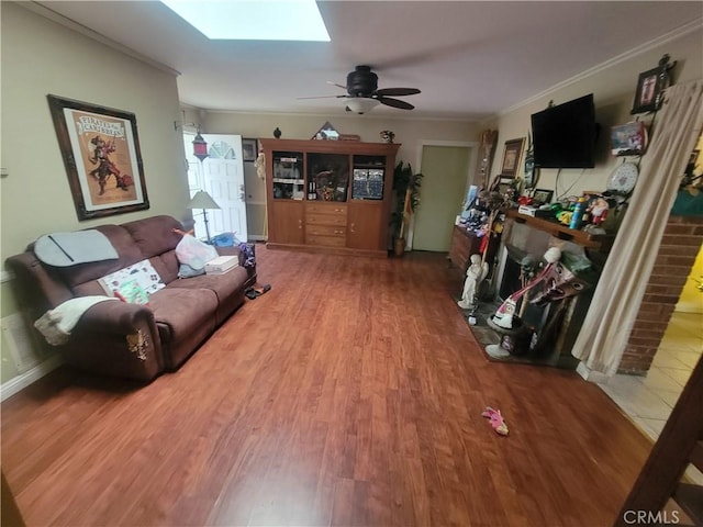 living room with ceiling fan, a skylight, crown molding, and hardwood / wood-style floors