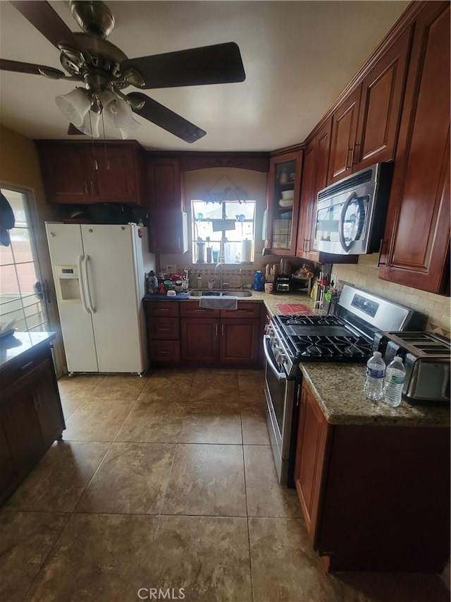 kitchen featuring ceiling fan, tile patterned floors, sink, stainless steel appliances, and light stone counters