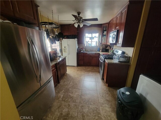 kitchen featuring ceiling fan, light stone countertops, light tile patterned flooring, and stainless steel appliances