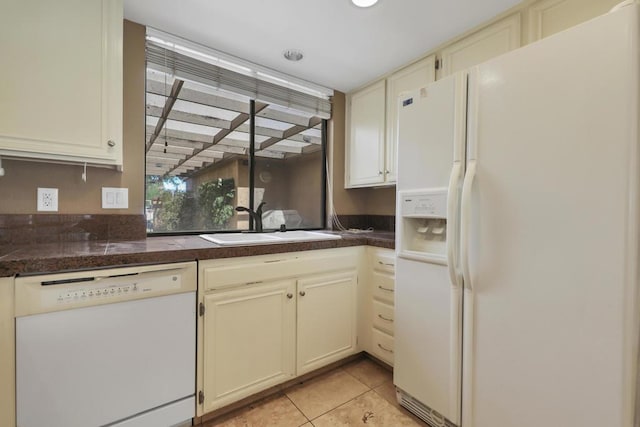 kitchen with cream cabinetry, sink, white appliances, and light tile patterned flooring