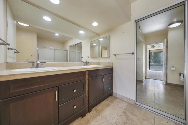 bathroom featuring a shower with shower door, vanity, and ceiling fan