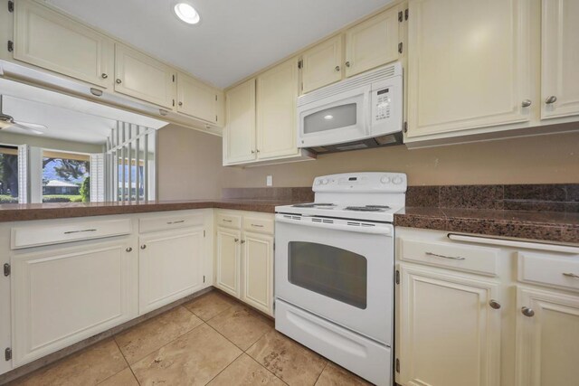 kitchen featuring ceiling fan, light tile patterned floors, cream cabinetry, and white appliances